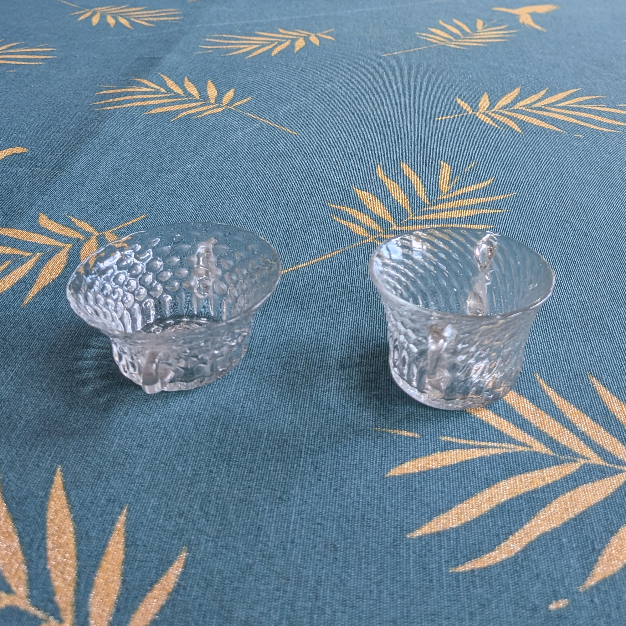 Side view of two small clear crystal bowls showing their different shapes and textured surfaces.
