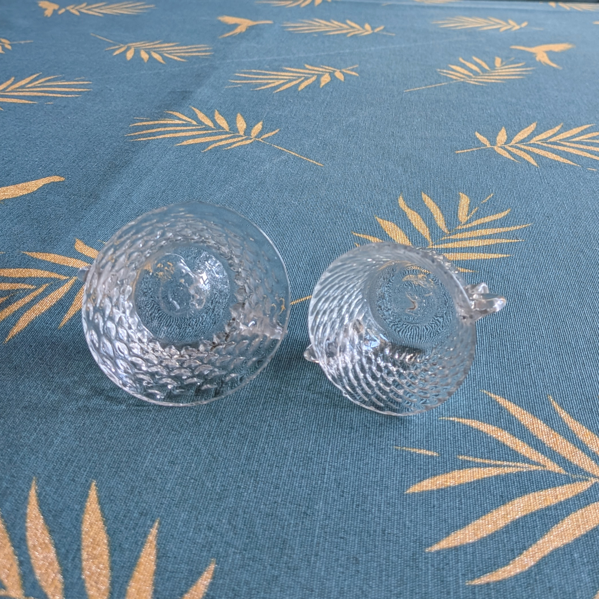 Two small clear crystal bowls tilted to show their bases and the texture around their lower edges.
