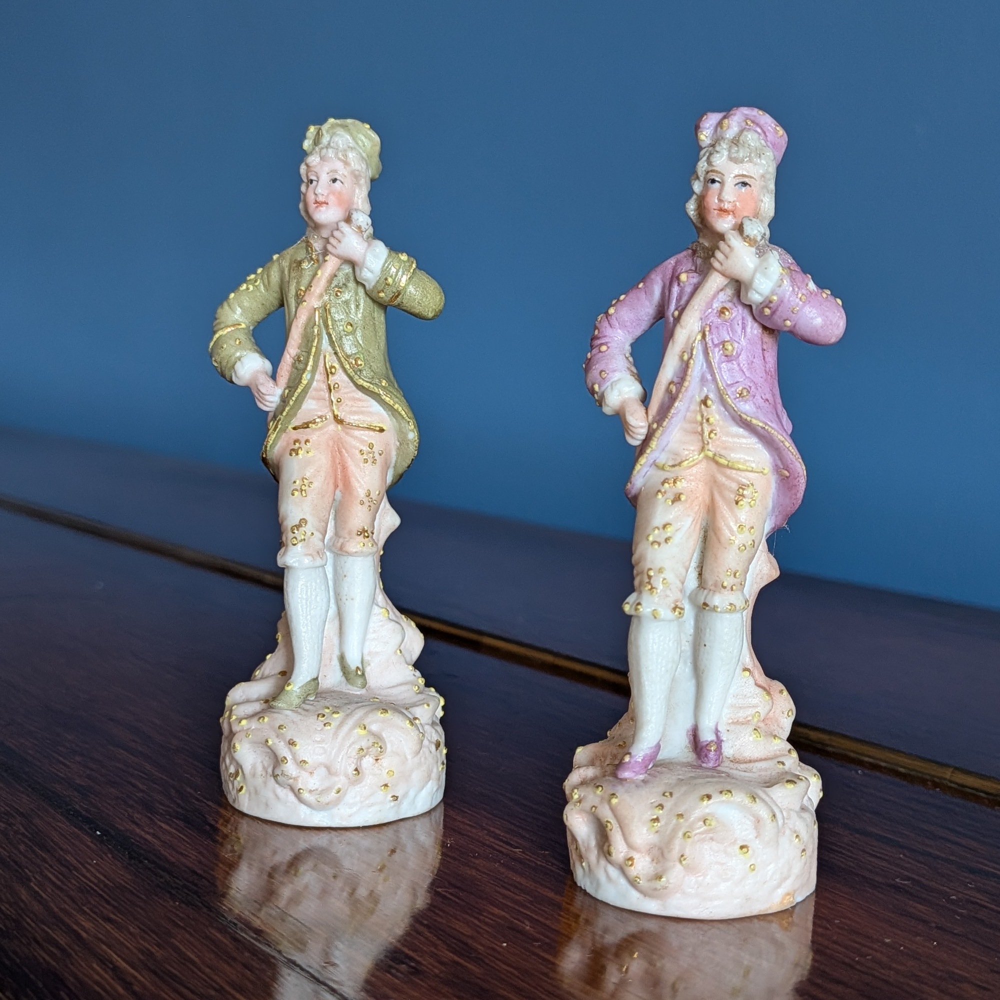 Front view of two courtier figurines in green and pink coats with gold-coloured details