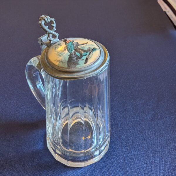 Opposite side of the glass beer tankard, showing its handle, faceted body and hinged lid.