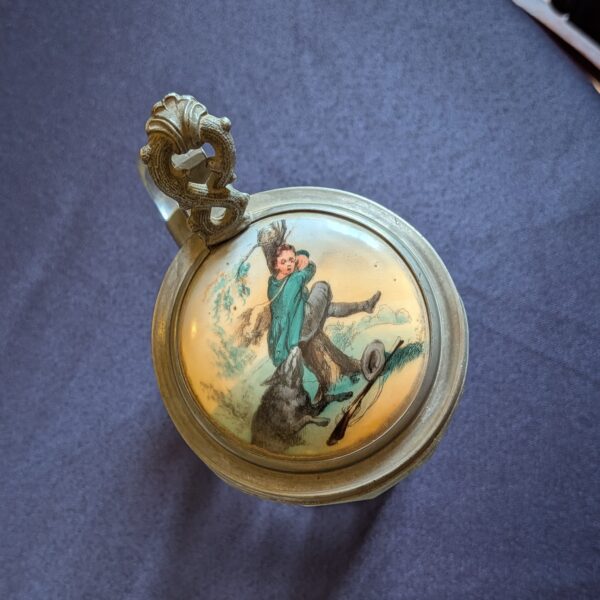 Close-up of the lid illustration showing a hunter and dog, with the decorative metal thumb lift.