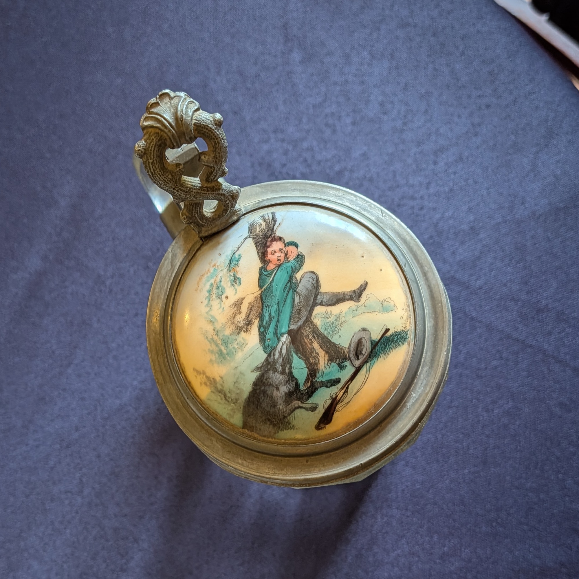 Close-up of the lid illustration showing a hunter and dog, with the decorative metal thumb lift.