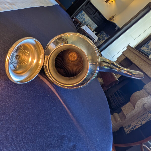Top view into the shorter metal pot, showing the interior and underside of the open lid.