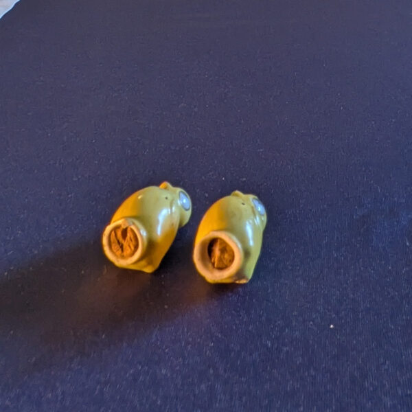 Closer underside view of the yellow chick shakers showing the base rims and brown material inside their openings.