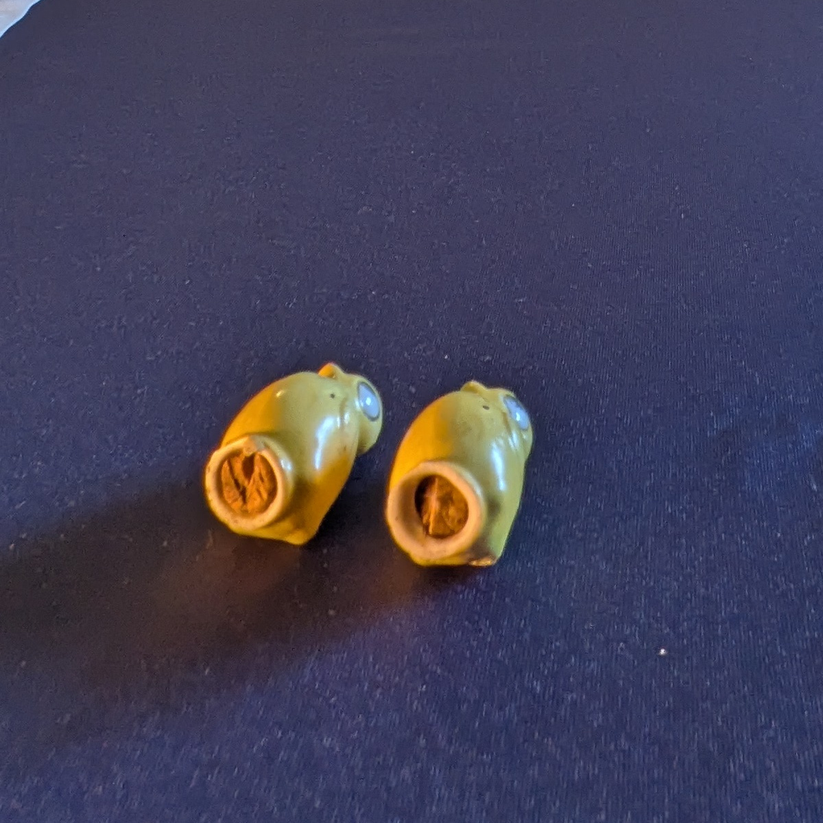 Closer underside view of the yellow chick shakers showing the base rims and brown material inside their openings.