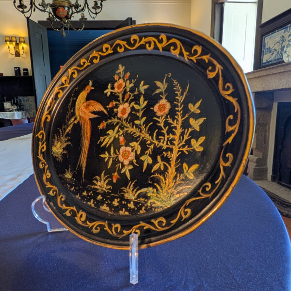 Angled view of the decorated oval tray showing its shallow raised rim and gold edging.
